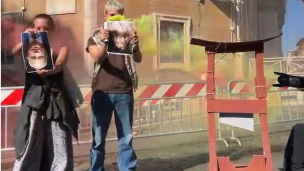 Manifestanti mostrano le foto di Meloni e Nordio a testa in giù